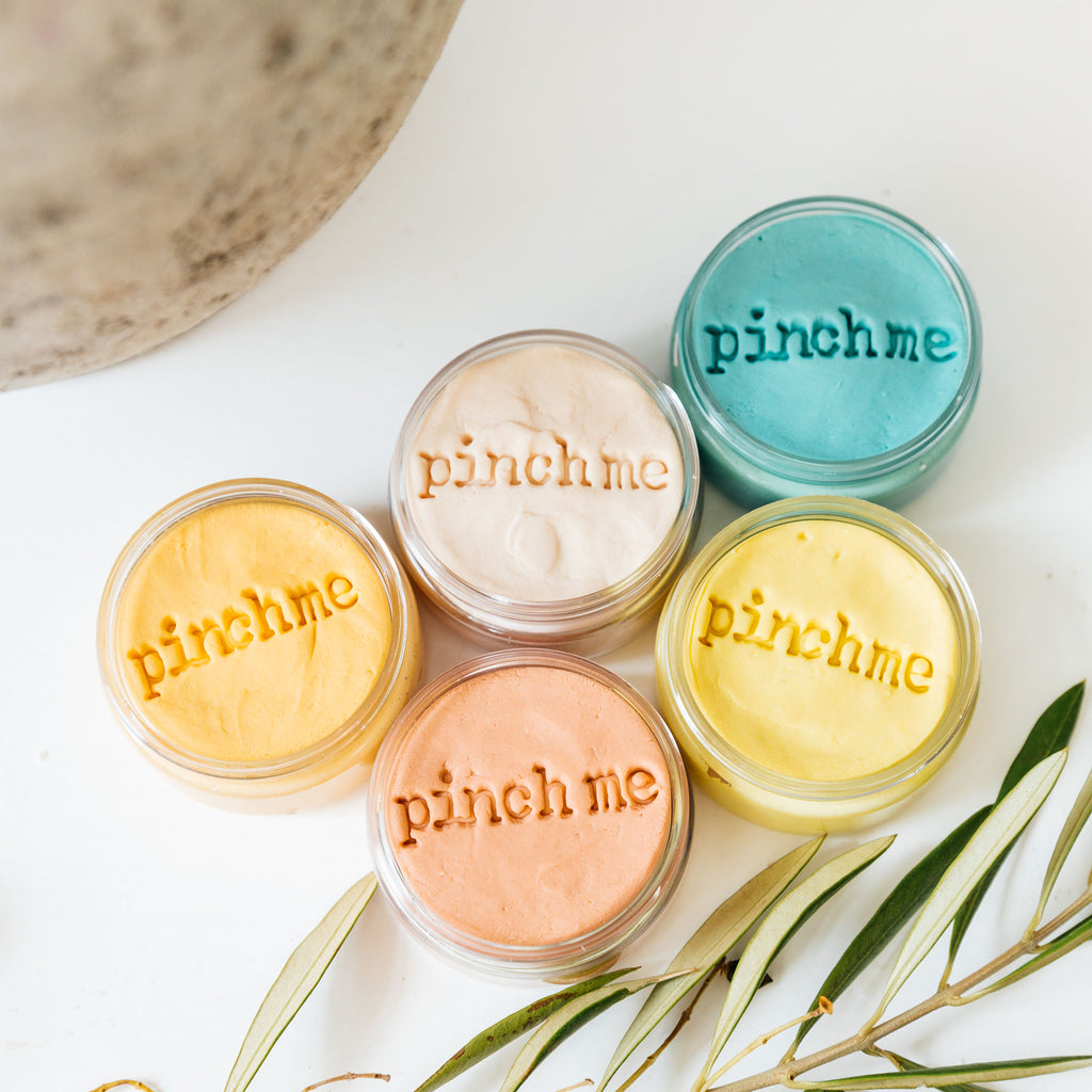 Five colorful jars of Pinch Me Therapy dough showing the Pinch Me stamp